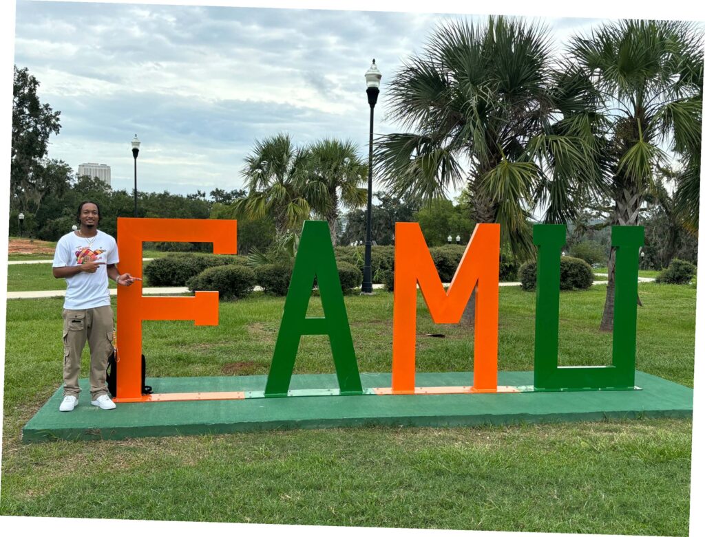 Scholarship recipient Jahnaiy Rodriguez standing next to a FAMU sign on campus.