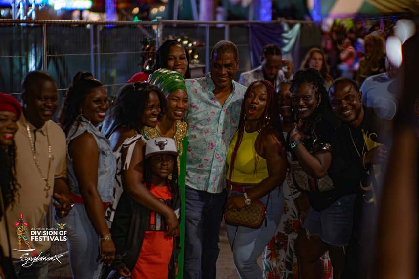 A large group of alumni, including the artist Reemah, smiling and posing for a photo at the Crucian Christmas Festival.